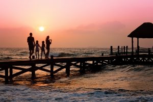 Familie am Steg von Strand bei Sonnenuntergang